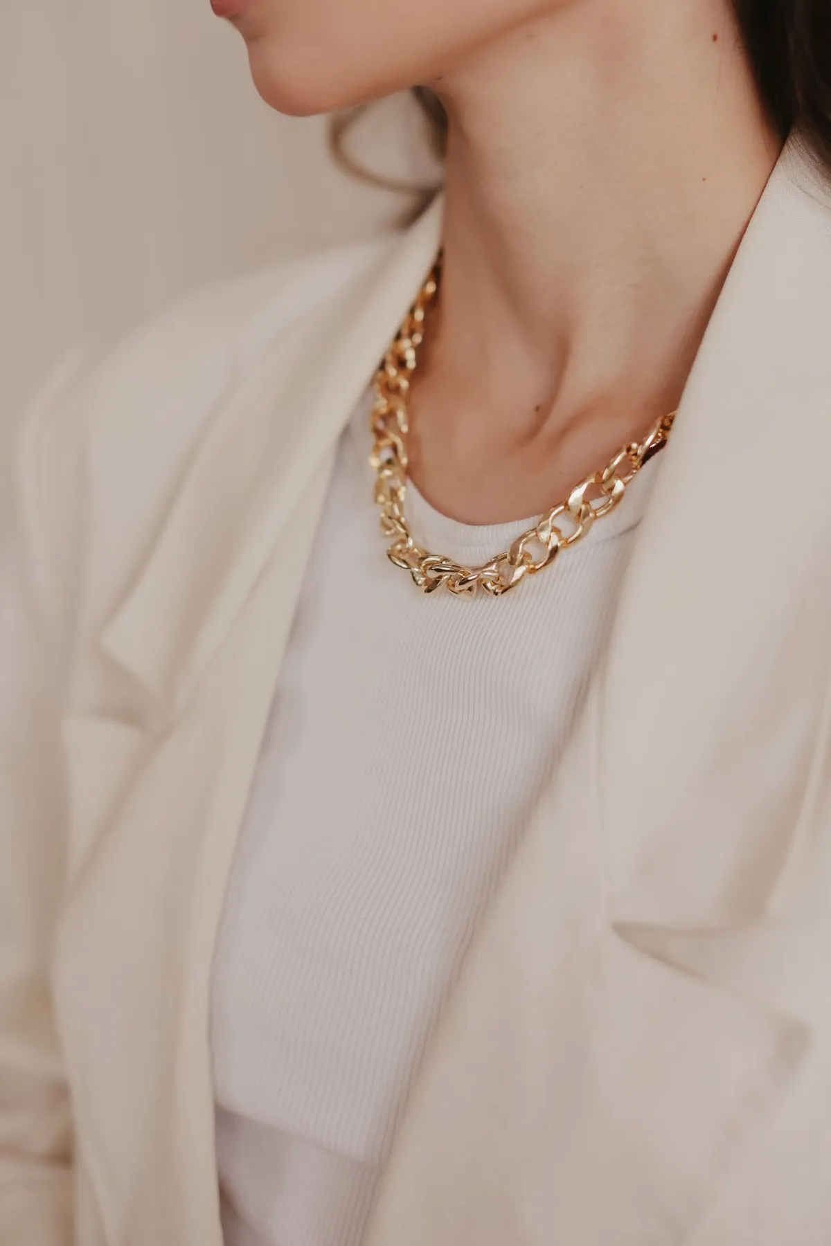 Mujer con chaqueta marfil y cadena gruesa de oro
